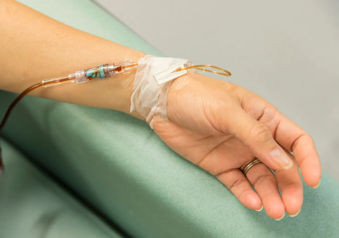 Kroplówki witaminowe Koło: dłoń z wenflonem i linią infuzyjną na podkładzie